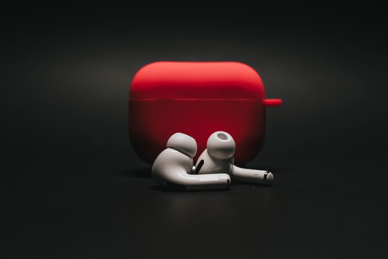 White earbuds with a red case on a black background